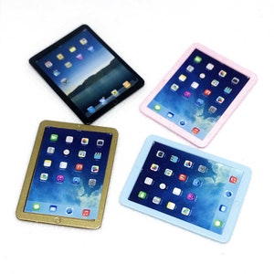 Pode incluir: Quatro computadores tablet em miniatura em diferentes cores: preto, dourado, rosa e azul claro. Cada tablet tem um ecrã que mostra uma variedade de ícones de aplicações.