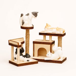 Könnte beinhalten: Ein Miniatur-Katzenbaum-Set mit vier Plattformen und verspielten Katzenfiguren. Das Set beinhaltet eine hohe Plattform mit einer grau-weißen Katze, eine rechteckige Plattform mit einer orange-weißen Katze, ein kleines Haus und eine Plattform mit einer schwarz-weißen Katze.