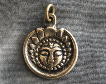 May include: A silver pendant with a detailed design of a face surrounded by a sunburst pattern.