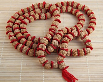 May include: A brown and red mala bead necklace with a tassel. The beads are made of wood and have a red thread wrapped around them.