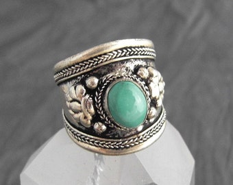 Può includere: Un anello d'argento con un designo ornato e una pietra turchese al centro.