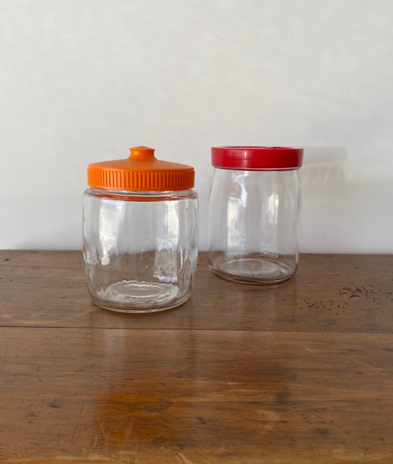中古のガラス瓶とプラスチック蓋のペア。オレンジと赤のレトロスタイル