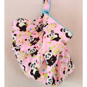 Könnte beinhalten: Eine rosa Stoffaufbewahrungstasche mit blauem Besatz und einem Pandabären-Druck. Die Tasche hängt an einem Haken.