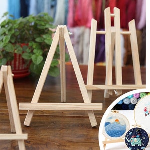 May include: Three wooden display stands of varying sizes. The stands are made of natural wood and have a simple, rustic design. The stands are perfect for displaying small items, such as artwork, photos, or crafts.