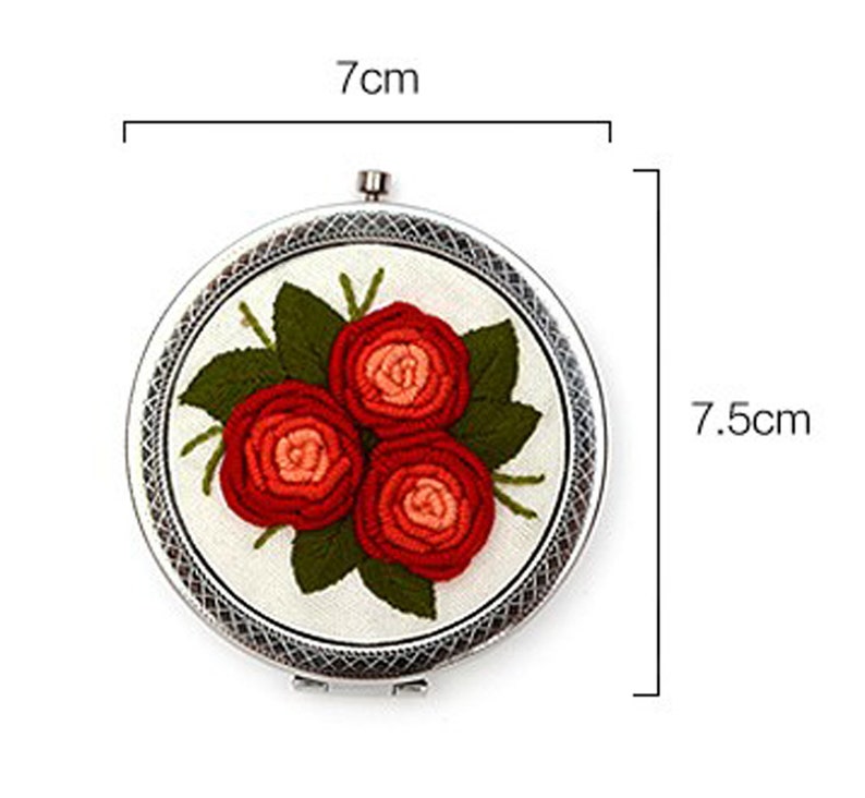 Op de afbeelding: Een ronde borduurring met een witte stoffen achtergrond en een bloemenontwerp van drie rode rozen met groene bladeren. De ring heeft een diameter van 7 cm.