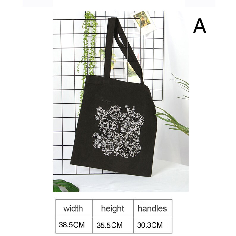 May include: Black canvas tote bag with white floral design. The bag has two handles and measures 38.5 inches wide, 35.5 inches high, and 30.3 inches for the handles.