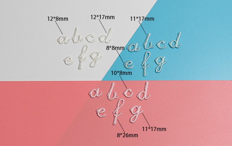 May include: White embroidered letters of the alphabet, a, b, c, d, e, f, and g, in various sizes, on a white, pink, and blue background. The letters are arranged in three rows, with the largest letters at the top and the smallest letters at the bottom. The letters are all in a cursive font.