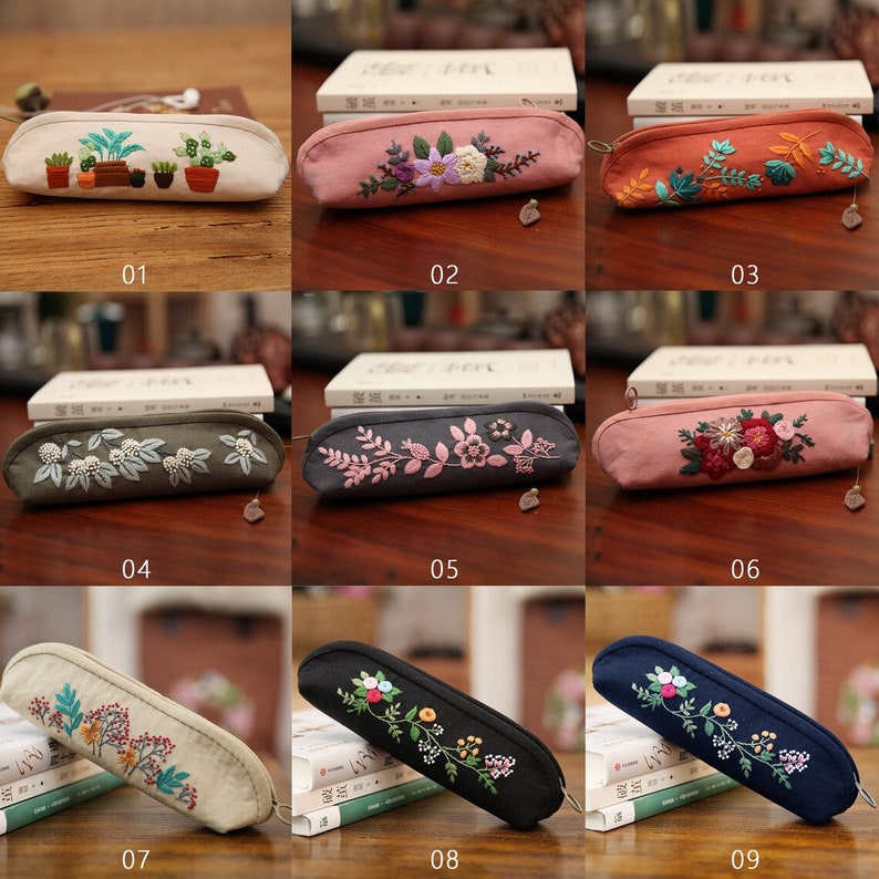 May include: Nine embroidered pencil cases with different floral and plant designs. The cases are made of canvas and have a zipper closure. The cases are displayed on a wooden surface.