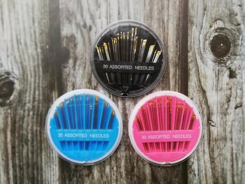 May include: Three round containers of assorted sewing needles. Each container has a different color: black, blue, and pink. Each container has the text "30 assorted needles".