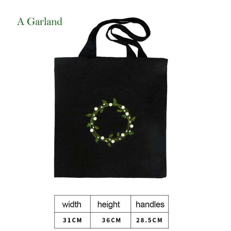 May include: Black canvas tote bag with a white and green embroidered floral wreath design. The bag has black handles and measures 31 inches wide, 36 inches high, and the handles are 28.5 inches long.