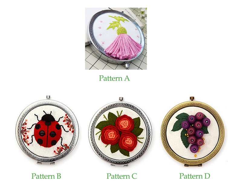 Op de afbeelding: Vier geborduurde compact spiegels met verschillende ontwerpen. De eerste spiegel heeft een roze distel, de tweede een rode lieveheersbeestje, de derde een bos rode rozen en de vierde een tros paarse druiven.