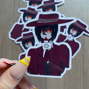 May include: A sticker featuring a cartoon character wearing a red suit, a black fedora, and sunglasses. The character is holding a cup of tea and has a red and white design on their face. The sticker is on a wooden surface.