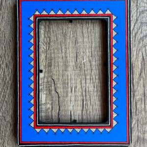 Op de afbeelding: Een blauwe fotolijst met een zwart, rood en wit geometrisch patroon rond de rand.