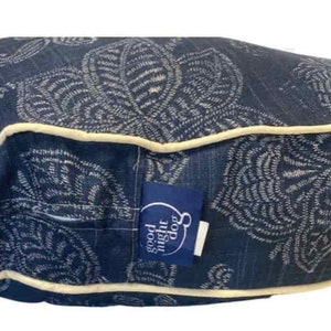 May include: A blue and white patterned dog bed with a cream colored border. The bed has a label that says "good night dog".