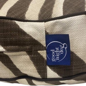 May include: A brown and white striped dog bed with a blue label that says "good night dog".