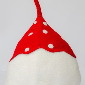 May include: A whimsical mushroom-shaped hat with a white base and a vibrant red cap adorned with white polka dots. The hat features a long, red, stem-like extension. This playful accessory is perfect for costume parties or themed events.