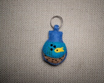 May include: Blue felt keychain shaped like a fishbowl with a yellow fish and green seaweed inside.