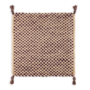 May include: A square woven rug with a checkered pattern in beige and burgundy. The rug has tassels on each corner.