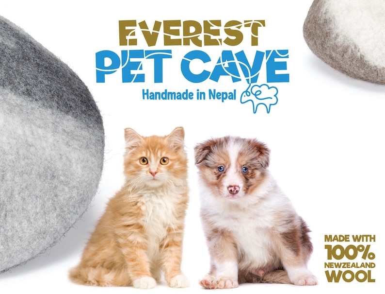 K&ouml;nnte beinhalten: Eine flauschige orangefarbene Katze und ein braun-wei&szlig;er Welpe sitzen vor zwei grauen Filzh&ouml;hlen f&uuml;r Haustiere. Der Text lautet EVEREST PET CAVE Handmade in Nepal und MADE WITH 100% NEWZEALAND WOOL. Der Hintergrund ist wei&szlig; und die Artikel sind aus Wolle.