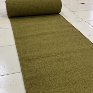 Peut inclure: Un tapis de couloir vert olive déroulé sur un sol carrelé. Le tapis est enroulé à une extrémité. Il est fait d'un matériau tissé et a un aspect texturé. Le tapis est de couleur unie.