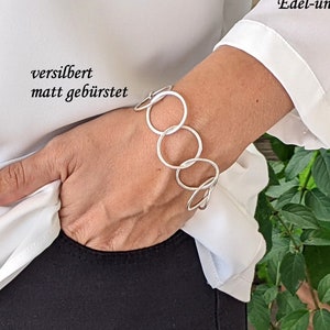 Könnte beinhalten: Ein silbernes Armband mit einer Kette aus verbundenen Kreisen. Das Armband ist als "versilbert matt gebürstet" beschrieben, was "versilbert matt gebürstet" bedeutet.