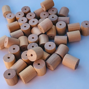 May include: A large pile of natural wood beads, all the same size and shape. The beads are a light brown colour and have a smooth, polished finish.