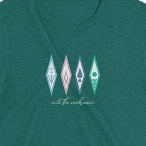 Puede incluir: Camiseta de manga corta de color verde azulado con un gr&aacute;fico de cuatro formas de diamante de colores y el texto "into the unknown".