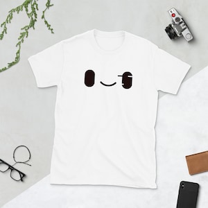 May include: White t-shirt with a black winking face graphic.