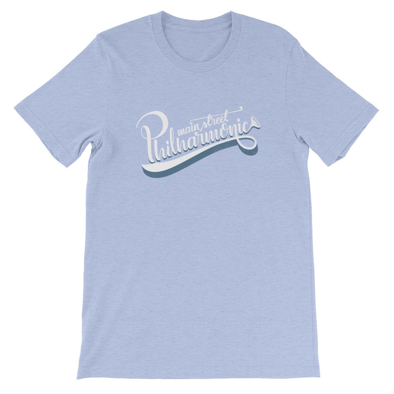 May include: Light blue t-shirt with a white graphic that says "main street philharmonics" in a stylized font.