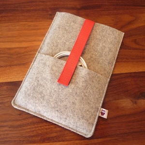 May include: A gray felt pouch with a red strap and a small owl logo. The pouch is designed to hold a white cord or cable.