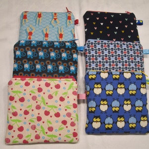 以下が含まれることがあります： さまざまなパターンが施された、ファスナー付きの布製のポーチが6つあります。ポーチは互いに積み重ねられています。パターンには、青と白の波模様、青と黒の猿模様、ピンクと白のチェリー模様、青と黒のフクロウ模様、青と白のドット模様、黒と白のハート模様があります。