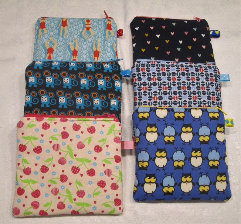 以下が含まれることがあります： さまざまなパターンが施された、ファスナー付きの布製のポーチが6つあります。ポーチは互いに積み重ねられています。パターンには、青と白の波模様、青と黒の猿模様、ピンクと白のチェリー模様、青と黒のフクロウ模様、青と白のドット模様、黒と白のハート模様があります。