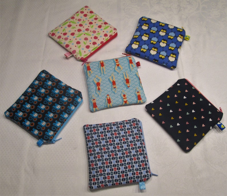 以下が含まれることがあります： さまざまなパターンが付いたジッパー付きポーチが6つあります。ポーチは布製で、青、ピンク、赤、白、黒など、さまざまな色があります。