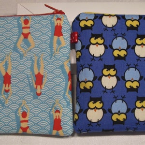 以下が含まれることがあります： 異なるパターンを持つジッパー付きポーチ2つ。1つのポーチは、白い波模様と赤いスイマーが描かれた青色。もう1つのポーチは、白いフクロウ模様が描かれた青色です。
