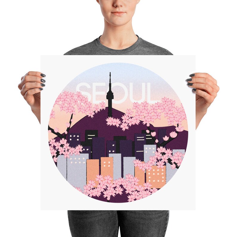 May include: A circular design featuring a cityscape with a tall tower, surrounded by pink cherry blossoms. The text "SEOUL" is written in white against a light blue background.