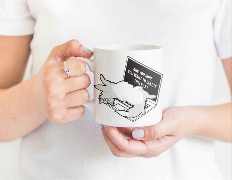 May include: White ceramic mug with a black and white illustration of a cat on a laptop. The laptop screen says "Are you sure you want to delete this file?"