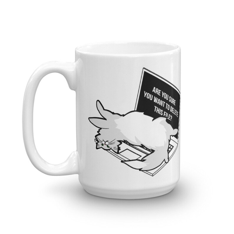 May include: White ceramic mug with a black and white illustration of a cat lying on a laptop. The laptop screen displays the text "Are you sure you want to delete this file?"