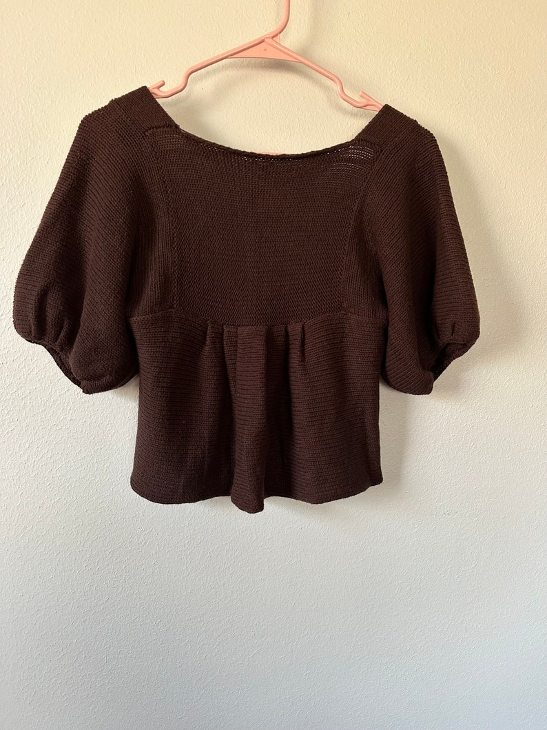 May include: A brown knitted sweater with a scoop neck and short puff sleeves.