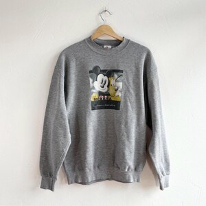 May include: Gray sweatshirt with a graphic print of Mickey Mouse and Goofy. The print features a cartoon image of Mickey Mouse and Goofy standing together. The text "Mickey & Goofy" is printed below the image.