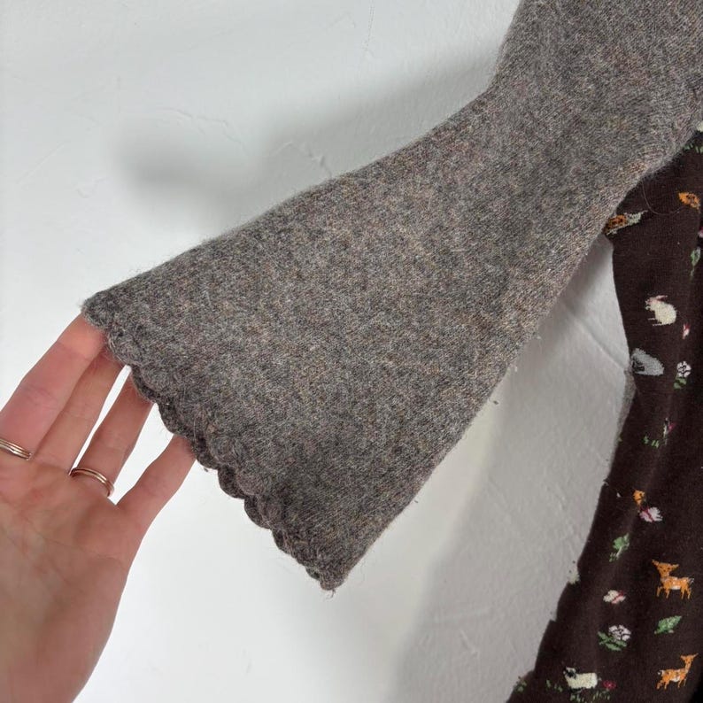 May include: A brown sweater with a scalloped edge and a brown and white patterned fabric underneath.