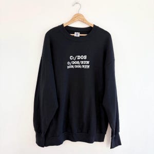 May include: Black sweatshirt with a white graphic print that reads "C:/DOS C:/DOS/RUN RUN/DOS/RUN".