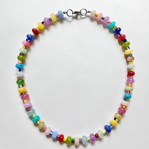 May include: A colorful beaded necklace with a variety of small, round beads in shades of red, yellow, green, blue, pink, and purple. The necklace has a silver-colored clasp and is displayed against a white background. The beads are approximately 0.25 inches in diameter.
