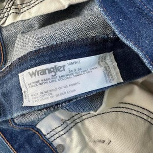 May include: Blue denim jeans with a white care label that reads "Wrangler 13MWZ 35 X 30 Machine Wash Hot and Inside Out First Three Times With Like Colors, Tumble Dry Made in Mexico of US Fabric 100% Cotton Exclusive of Decoration"