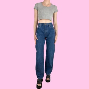 May include: A pair of dark blue denim jeans with a high waist and a straight leg fit. The jeans have a classic five-pocket style and a button fly.