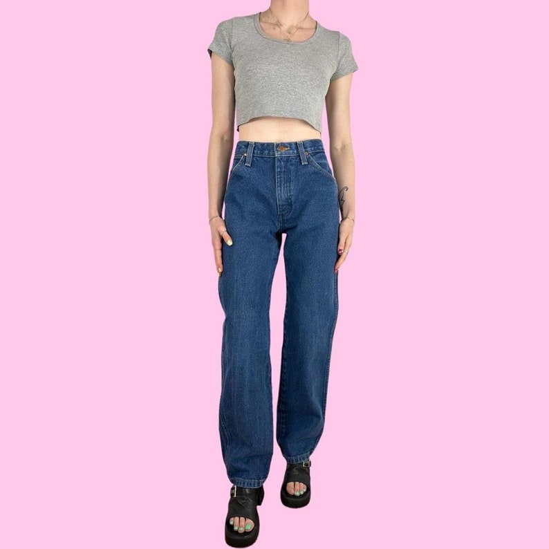 May include: A pair of dark blue denim jeans with a high waist and a straight leg fit. The jeans have a classic five-pocket style and a button fly.