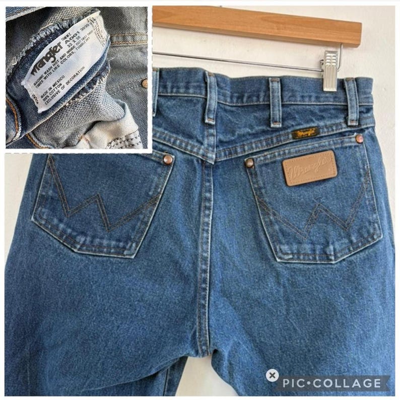 May include: Close-up of the back of blue denim Wrangler jeans. The jeans have two back pockets with the Wrangler logo stitched on them. A leather patch with the Wrangler logo is centered above the right pocket. The jeans are size 32x30.