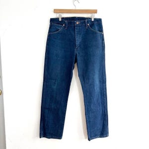 May include: A pair of dark blue denim jeans with a button fly and five pockets.