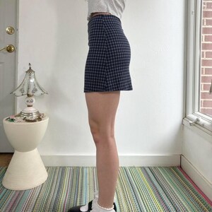 Puede incluir: Minifalda a cuadros azul marino y blanco. La falda es entallada y presenta un patr&oacute;n de cuadros cl&aacute;sico. La vista lateral resalta su forma y dise&ntilde;o. Una prenda vers&aacute;til para varios conjuntos. La longitud es de aproximadamente 40 cm.