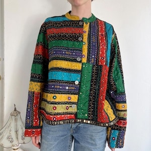 May include: A long-sleeve quilted jacket featuring a vibrant patchwork design with vertical stripes in red, green, yellow, blue, and purple. The garment includes intricate embroidery, small circular mirror accents, and a front button closure.