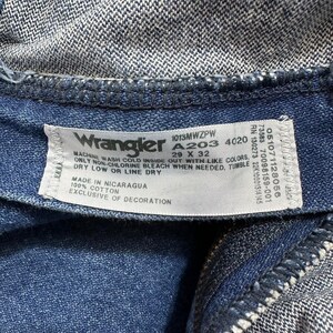 May include: A white care label with blue text for Wrangler jeans. The label includes the size 29 x 32, the style number A203, and washing instructions. The label is made in Nicaragua and is 100% cotton.